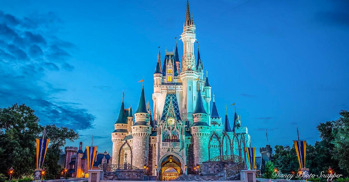 Cinderella Castle shines at dusk in Disney World, with a glowing blue sky and lush trees—a must-see for park-goers seeking magic.