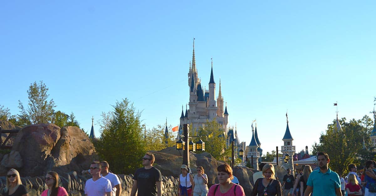 Guests stroll through Walt Disney World as Cinderella Castle towers ahead, enjoying the magic even on bustling days under sunny skies.