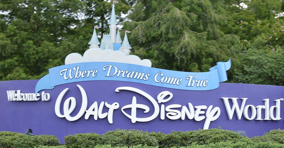 The iconic purple "Welcome to Walt Disney World, Where Dreams Come True" sign greets guests with a castle above the entrance.