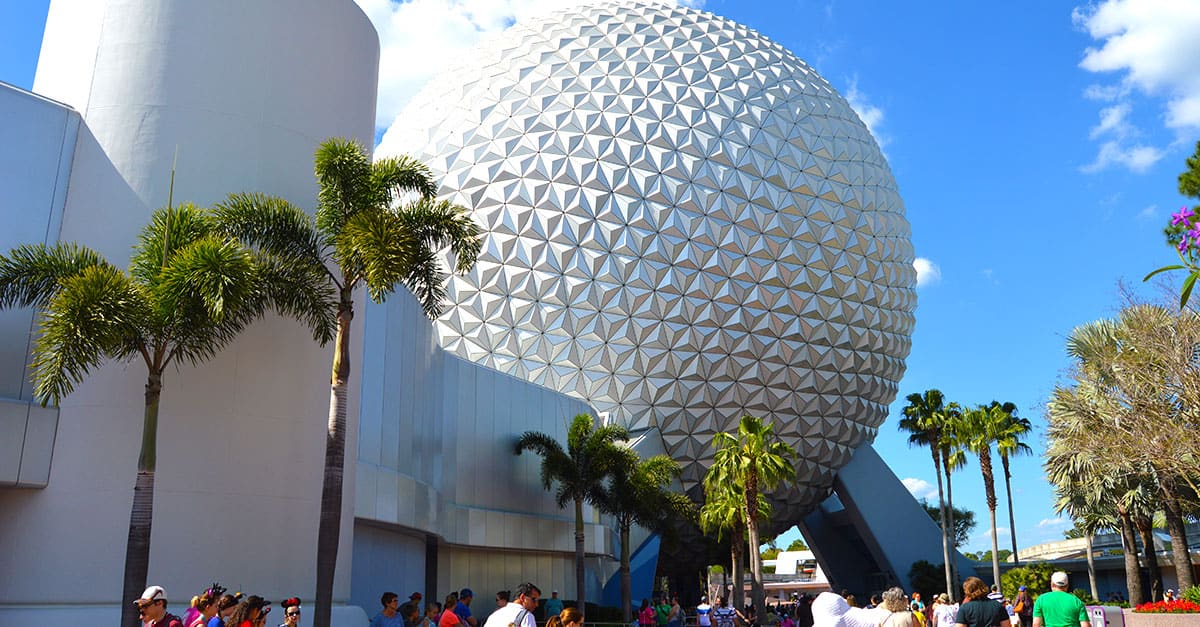 Guests stroll beside Spaceship Earth at Epcot, framed by palm trees and the excitement of Future World attractions.