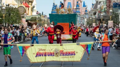 Disney characters, including Woody, Jessie, and Miguel, parade down Main Street in the lively Disney Parades "Adventure Friends Cavalcade," with performers, a festive banner, cheering crowds, and the castle towering in the background.