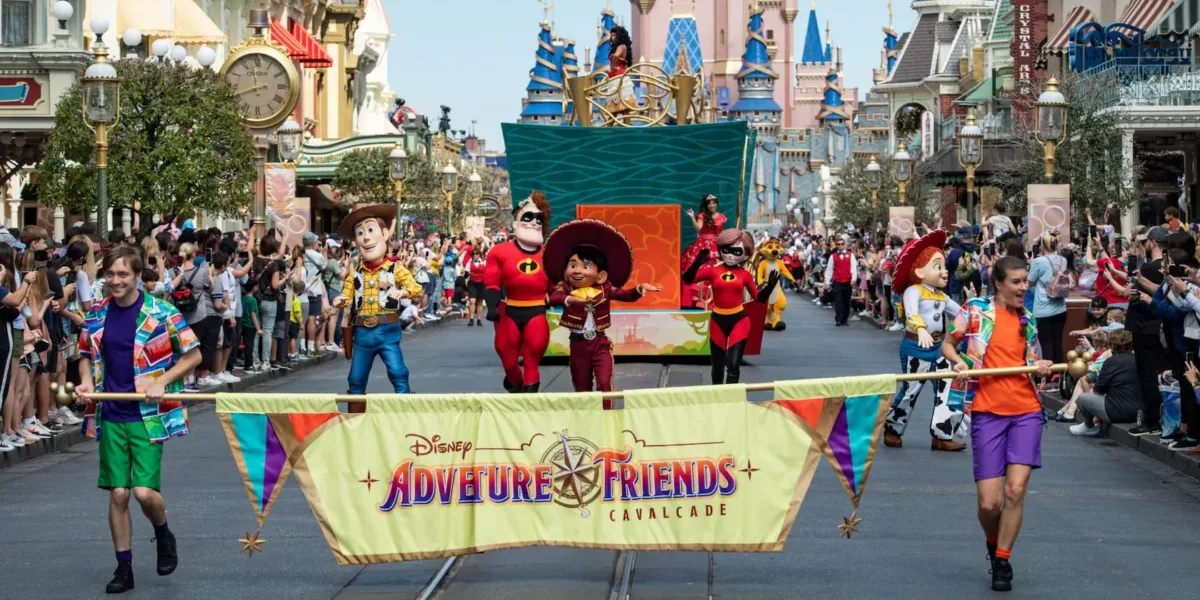 Disney characters, including Woody, Jessie, and Miguel, parade down Main Street in the lively Disney Parades "Adventure Friends Cavalcade," with performers, a festive banner, cheering crowds, and the castle towering in the background.
