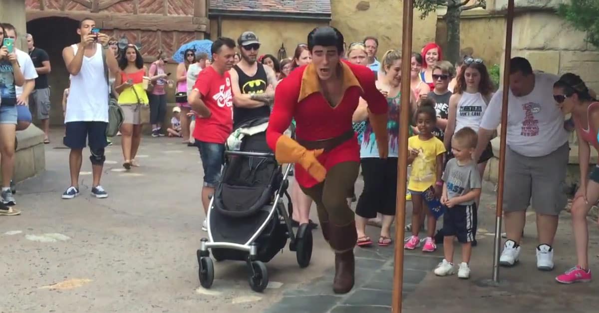 Gaston charges toward the camera, captivating guests who eagerly watch and snap photos during a lively theme park event.