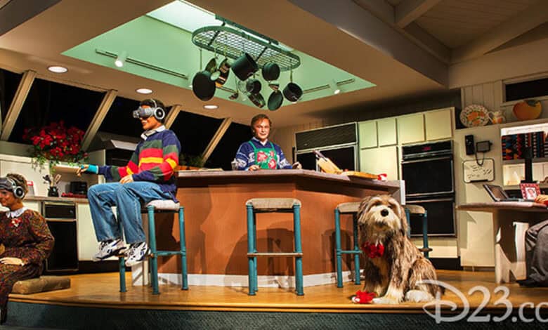 A kitchen scene features animated human figures in 1990s attire using various gadgets, a dog with a red bow sits in front, and a woman works at a computer; the room, filled with Tomorrowland Secrets, is decorated for Christmas.
