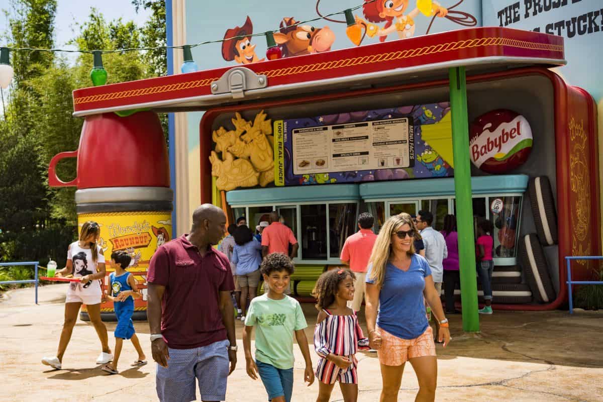 A family strolls by the vibrant Toy Story-themed lunchbox snack stand in Pixar Pier at Disney California Adventure Park.
