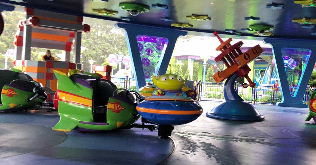 Alien Swirling Saucers ride at the amusement park, showcasing vibrant spaceships with playful green Toy Story aliens in dynamic blue and green vehicles.