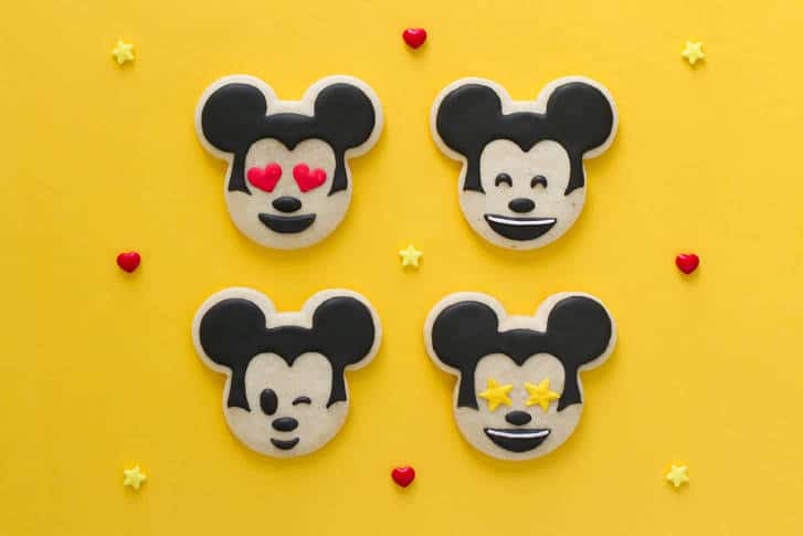 Mickey-shaped lemon cookies with playful expressions, set on a bright yellow backdrop with hearts and stars, Disney magic-style.