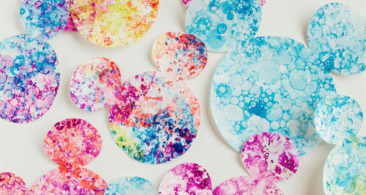 Playful, overlapping watercolor bubbles in vibrant colors capture the joyful spirit of Mickey Mouse at Disney Parks.