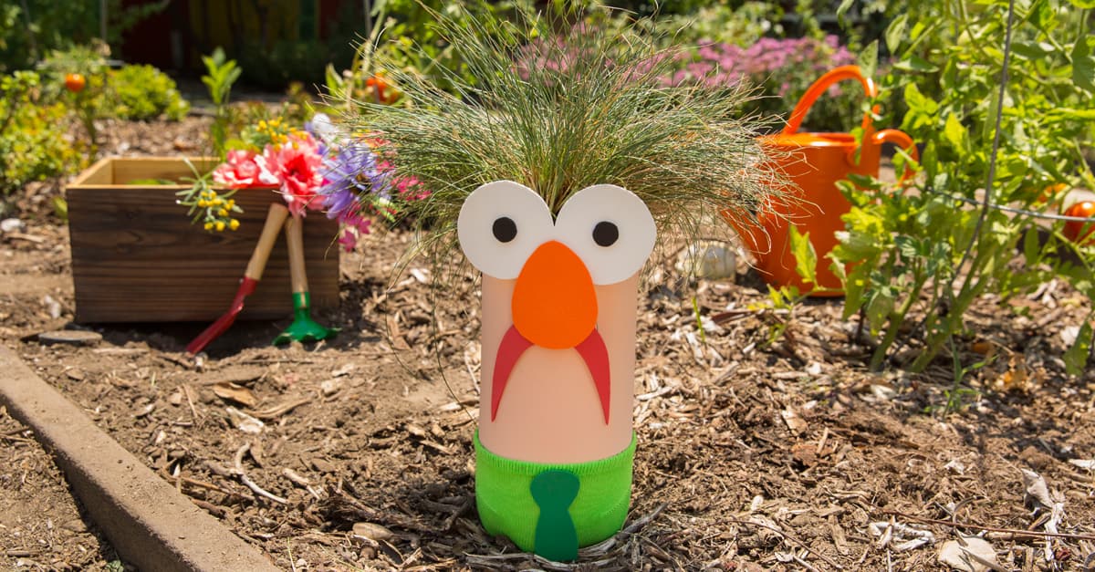 A whimsical bottle planter with grassy hair and a cheery face greets visitors like a garden mascot at the park’s playful gardens.