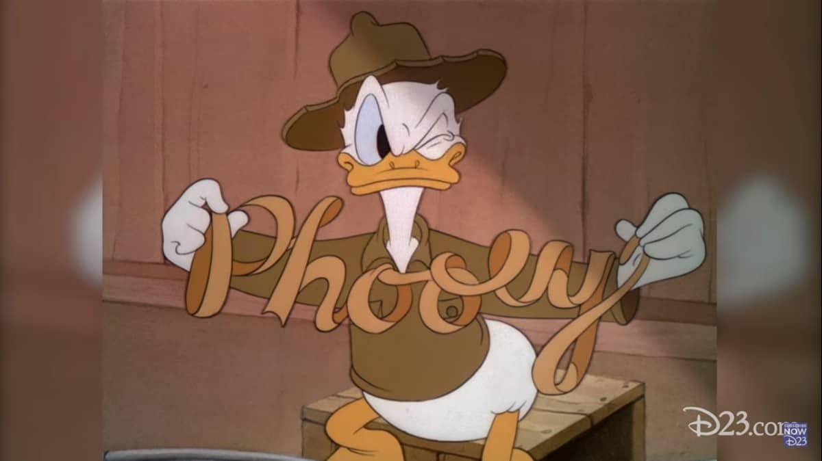 Donald Duck in his brown scout outfit holds a “Phony” ribbon, looking grumpy during a classic Disney Parks moment.