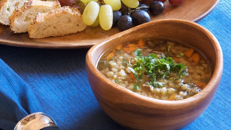 Hearty vegetable soup with herbs in a wooden bowl, served with bread and grapes at King Stefan’s Banquet Hall in Magic Kingdom.