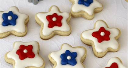 Festive star cookies with white icing, decorated with red and blue flowers—perfect for a Fourth of July celebration at Disney parks.