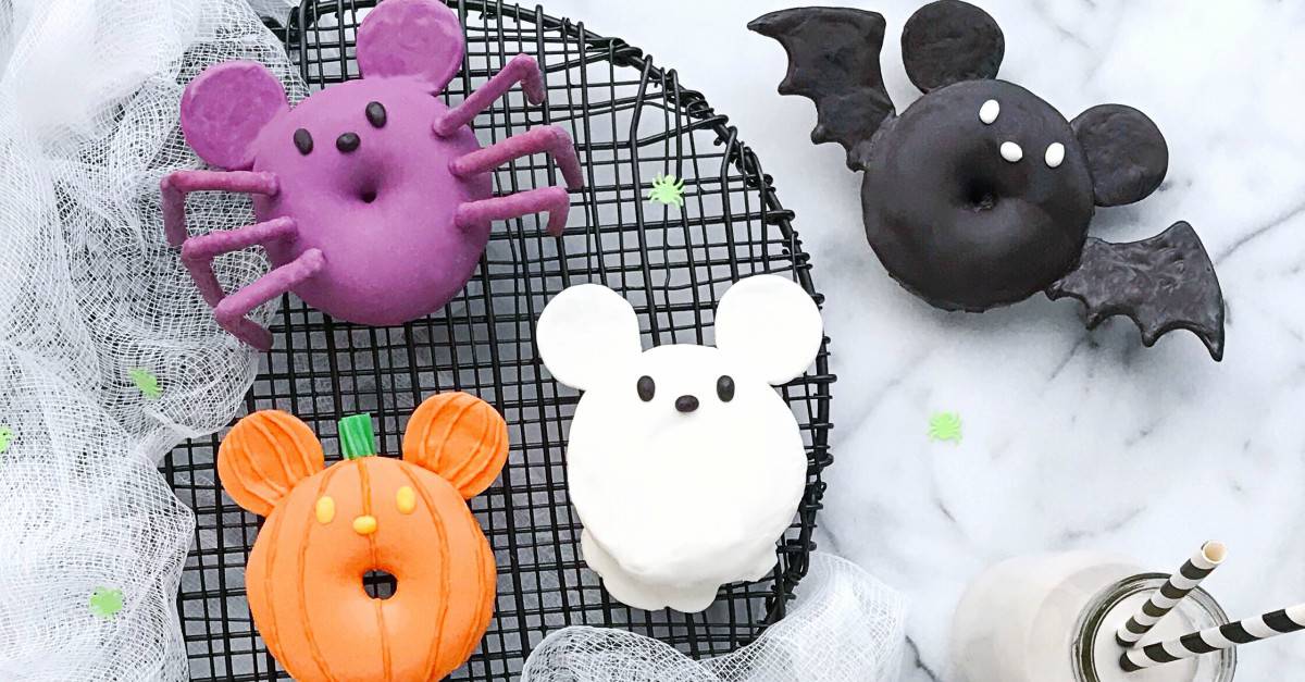 Four delightfully spooky donuts—animal and pumpkin shapes—await on a rack, inspired by Disney Parks’ Mickey Halloween treats.
