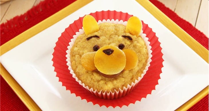 Winnie the Pooh cupcake in a red liner, with yellow ears and face details, made from an allergy-friendly corn muffin recipe.