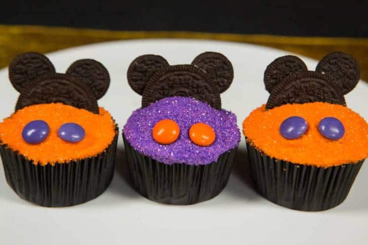 Halloween cupcakes inspired by Mickey Mouse, topped with Oreo ears, candy eyes, and festive sprinkles—perfect for Disney fans!.