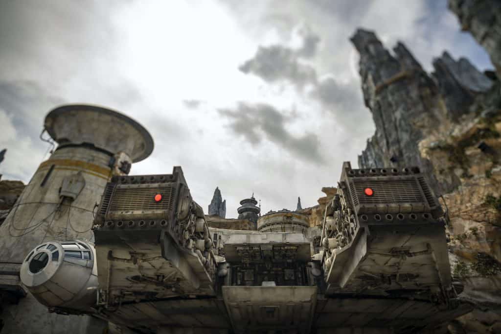The iconic Millennium Falcon rests in a dramatic, rocky setting beneath swirling clouds at Star Wars: Galaxy’s Edge, Hollywood Studios.