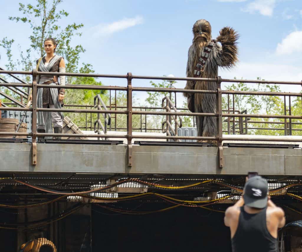 Rey and Chewbacca greet guests on the platform at Star Wars: Galaxy’s Edge in Disney’s Hollywood Studios as fans snap photos.