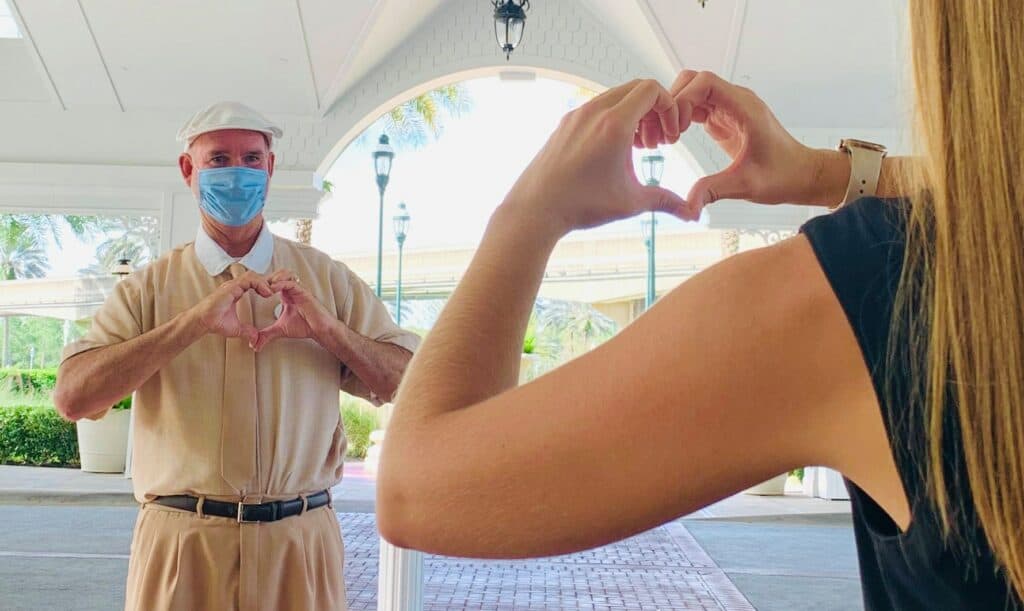 Guests at Disney’s Grand Floridian Resort exchange heart-shaped hand signs outside, sharing Disney magic together.