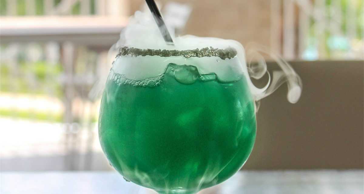 Witches Caldron Cocktail with swirling smoke and sugared rim, served at Margaritaville Resort Orlando—Halloween magic in a glass!.