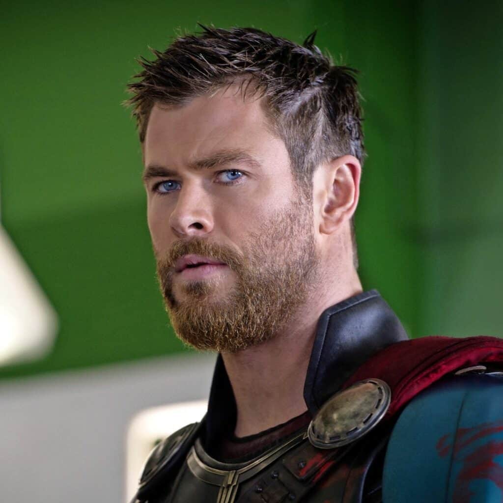 Thor lookalike with short brown hair and a beard in armor, striking a heroic pose before a vibrant green backdrop.