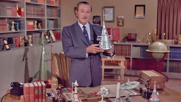 A Disney cast member displays a spaceship model, showcasing the park’s celebration of space-themed magic and adventure.