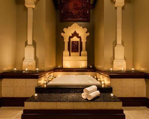 A lavish spa bath featuring rolled towels, glowing candles, and elaborate decor in a warmly lit space—an ideal retreat to recharge after an exciting day at Disney World for adults seeking relaxation beyond the parks.
