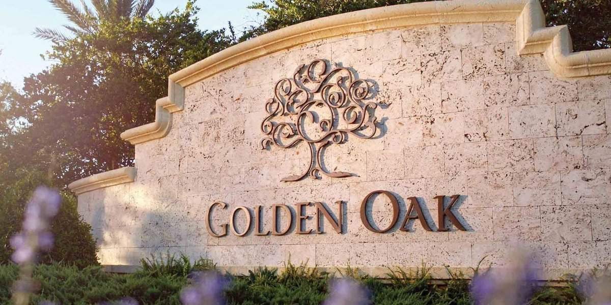A stone sign with an ornate tree design and the words "GOLDEN OAK" engraved on it, surrounded by greenery and purple flowers, sunlight shining from the left—perfect for those moving close to Disney’s magical bubble.
