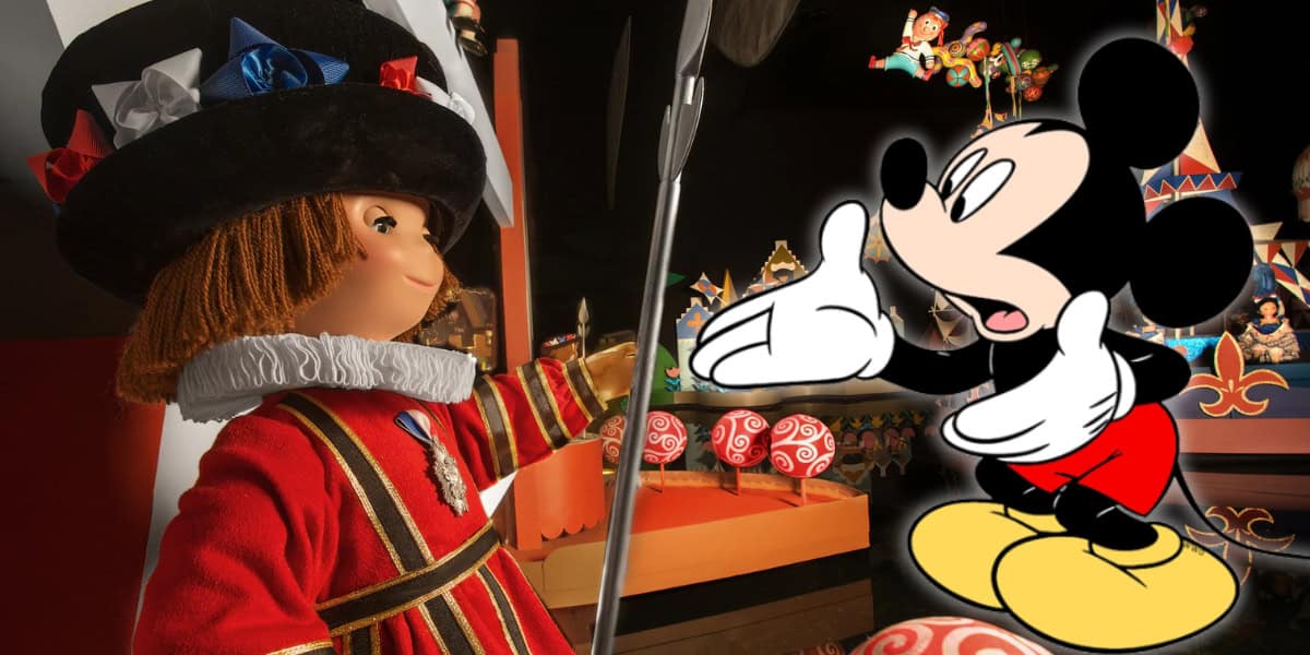 A colorful scene features an animated character in traditional attire engaging with Mickey Mouse. The character wears a red and gold outfit with a large black hat adorned with blue and red ribbons. Mickey Mouse, looking as animated and expressive as ever, stands with his arms open amidst the ongoing Disney rides refurbishment.