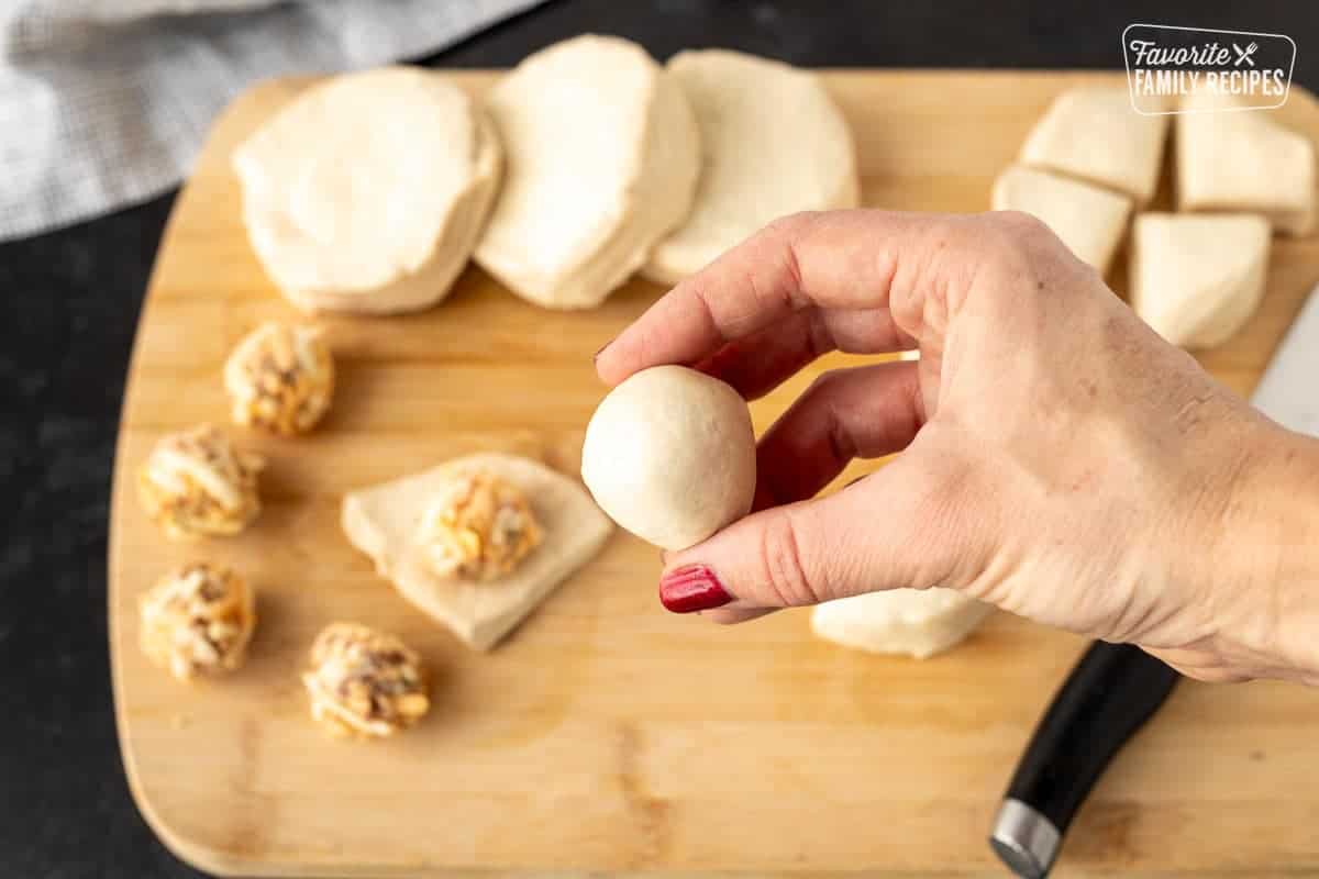 Hand holding a biscuit covered cheese ball.