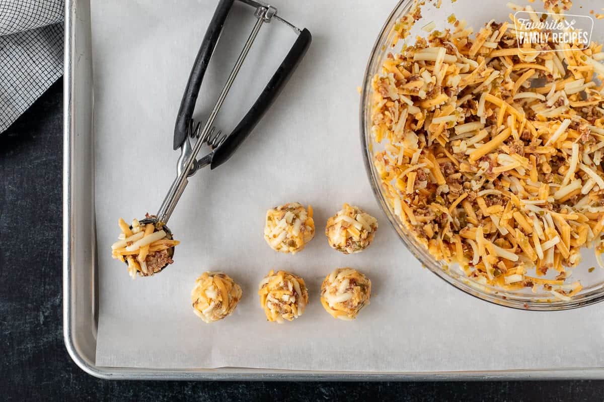 Carthay Circle Fried Biscuits taste exactly like the spicy, cheesy biscuits found at Disney's California Adventure restaurant. Perfect little bites that are super easy to make at home! Cookie sheet with scooped cheese filling, bowl of filling and a cookie scoop.