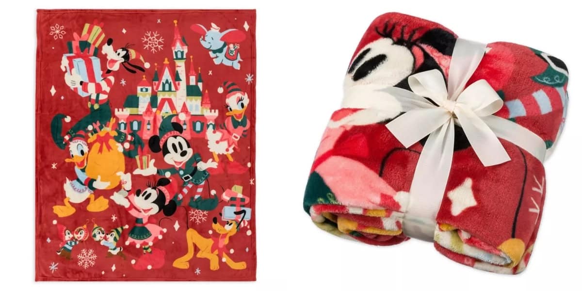 A red blanket featuring cartoon characters, including a mouse in a Santa outfit, a duck with a striped cane, and a dog with antlers standing near a decorated castle. The blanket is shown both spread out and rolled up, tied with a white ribbon.