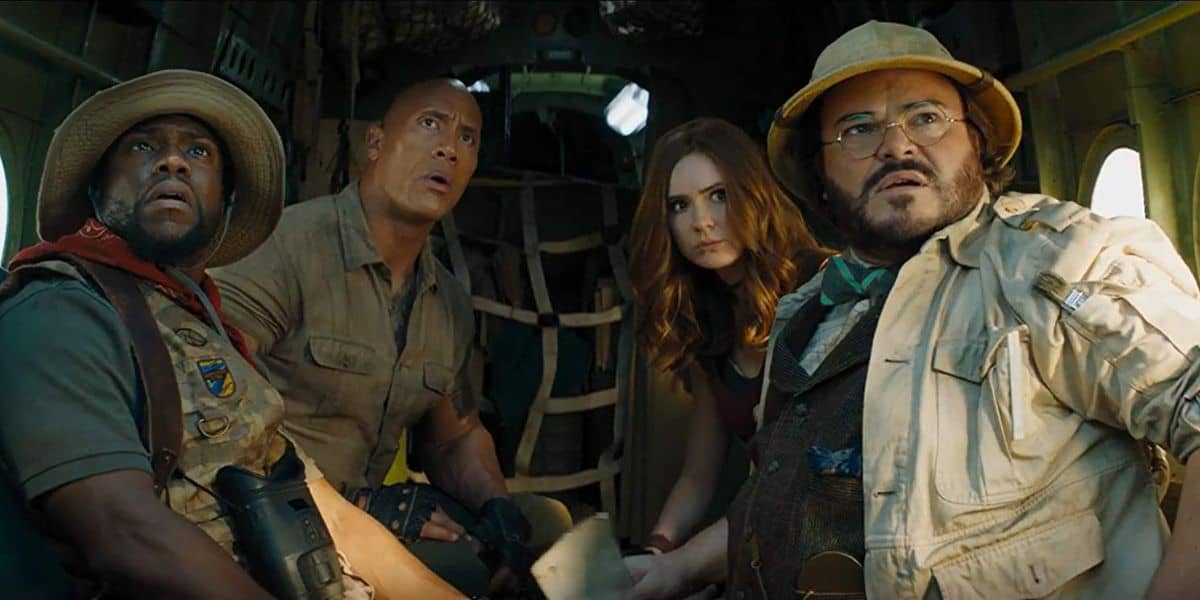 Four people in an adventurous setting look surprised inside a helicopter. They are dressed in explorer gear, with one wearing a safari hat and another holding maps. The scene suggests an action-packed moment.