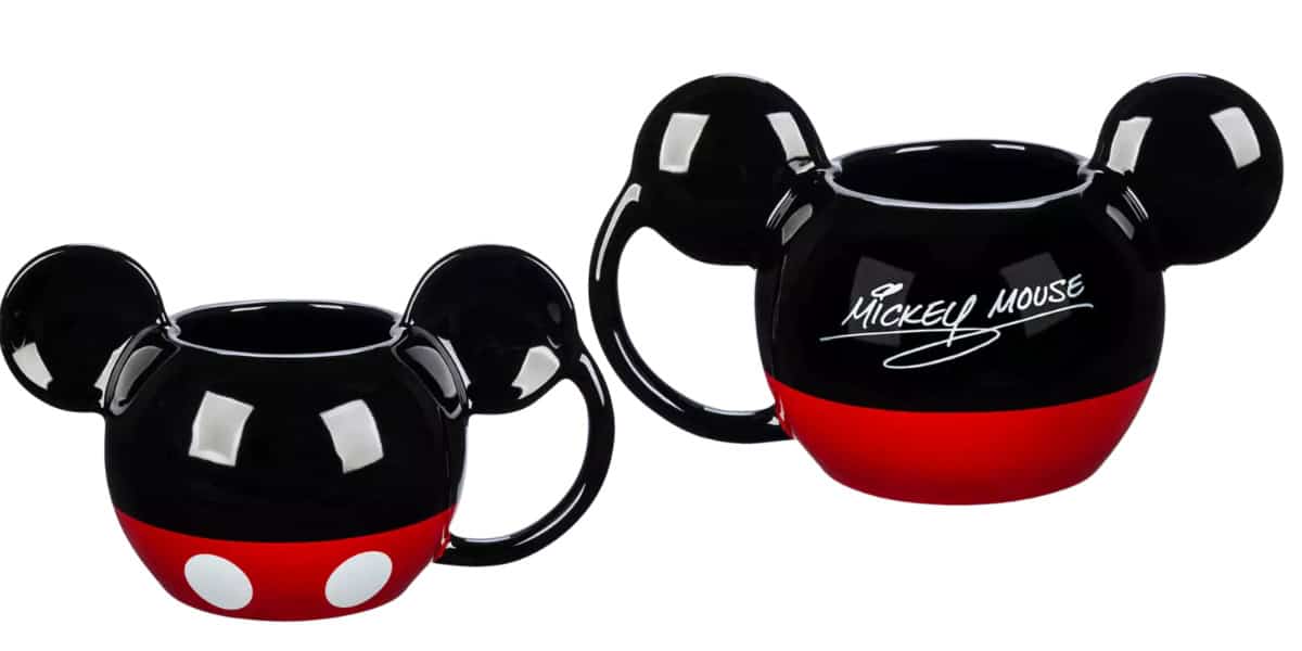Two black ceramic mugs shaped like Mickey Mouse's head with ears. One is smaller with red bottom and white dots, resembling Mickey's shorts. The larger one has "Mickey Mouse" written in white on the side. Both have handles.