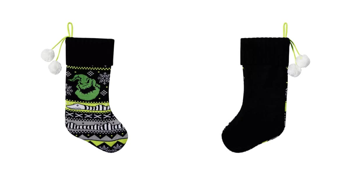 Two Christmas stockings: the left one features a green dragon design with geometric patterns, and the right is plain black. Both have green strings and white pom-poms for hanging.