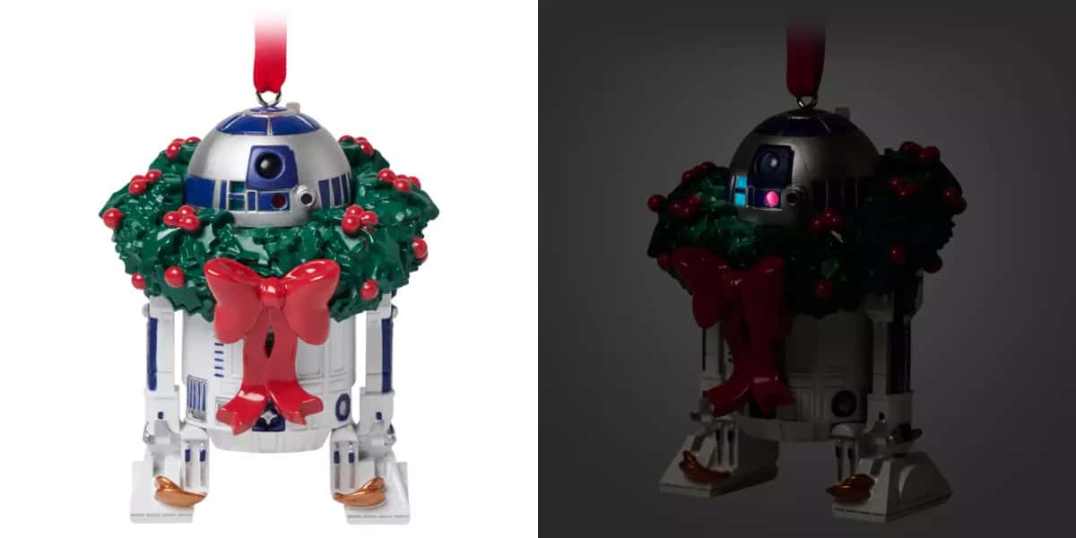 A Christmas tree ornament shaped like a robot, decorated with a green wreath and red bow, divided into two sections: the left is brightly lit, and the right is dimly lit with two glowing lights on the robot.