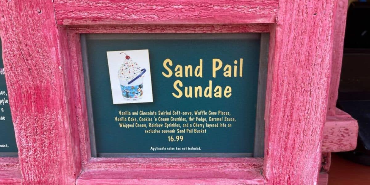 Sign for "Sand Pail Sundae" with a description: vanilla and chocolate soft-serve, waffle cone pieces, vanilla cake, cookies, cream crumble, fudge, caramel sauce, whipped cream, rainbow sprinkles, cherry, in a souvenir bucket. Price is $16.99.