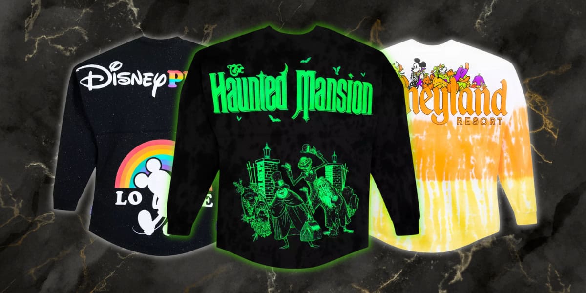 Three long-sleeve shirts featuring Disney designs: one with a white Mickey silhouette and rainbow on black, another with green "The Haunted Mansion" text and characters, and the last with yellow tie-dye and "Disneyland Resort" text.