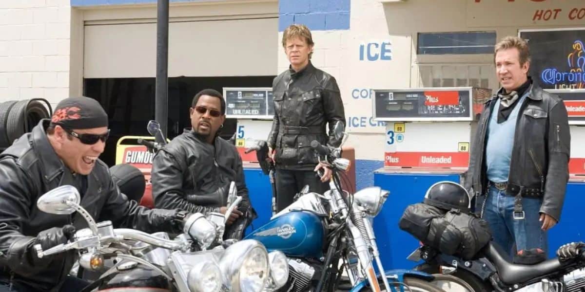 Four men in leather jackets, reminiscent of a Wild Hogs sequel, are at a gas station with motorcycles. One man sits excitedly on his bike, while the others watch with mixed expressions. The station features gas pumps and signs for ice and drinks.