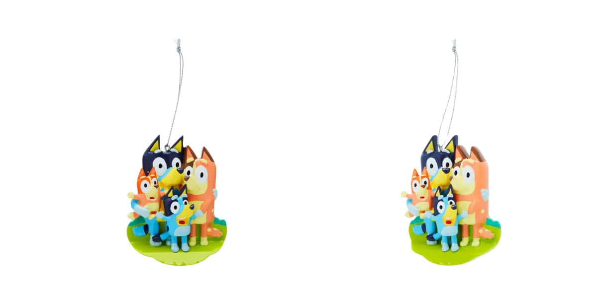 Two identical ornaments depicting cartoon dog characters, with blue and orange coats, standing together on a green base. They have friendly expressions and are hanging from thin strings, suggesting they are decorations or toys.