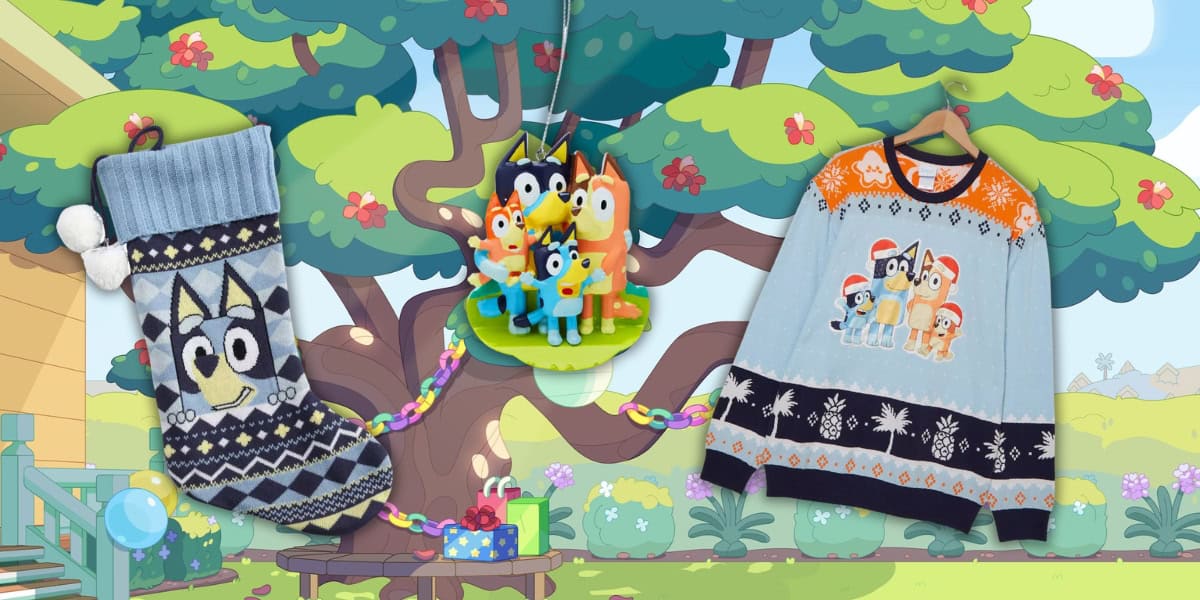 An animated scene features a cartoon tree. In the foreground are a blue patterned Christmas stocking, an ornament with cartoon dog characters, and a light blue sweater with the same characters. The background includes a small staircase and gifts.