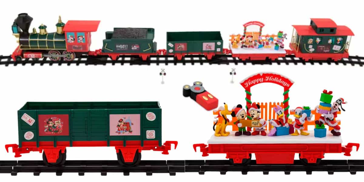 A festive toy train set on tracks featuring a green and red locomotive, carriages with holiday-themed decorations, and cartoon characters. The set includes a remote control and has festive designs like "Happy Holidays" signage.