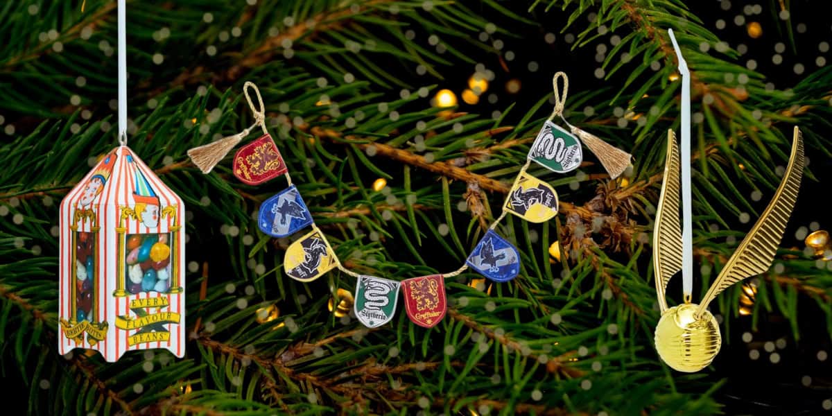 Christmas tree with Hogwarts-themed ornaments: a Honeydukes candy box, house banners garland, and a golden snitch. The tree is adorned with small gold lights, creating a festive atmosphere.