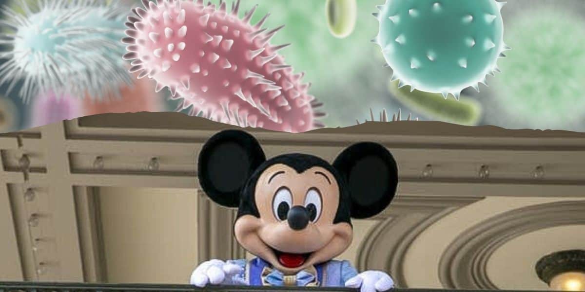 Mickey Mouse, wearing a blue outfit, is smiling and waving from a balcony. Above, colorful microscopic organisms with spiky textures are floating in a whimsical scene at Disney World.