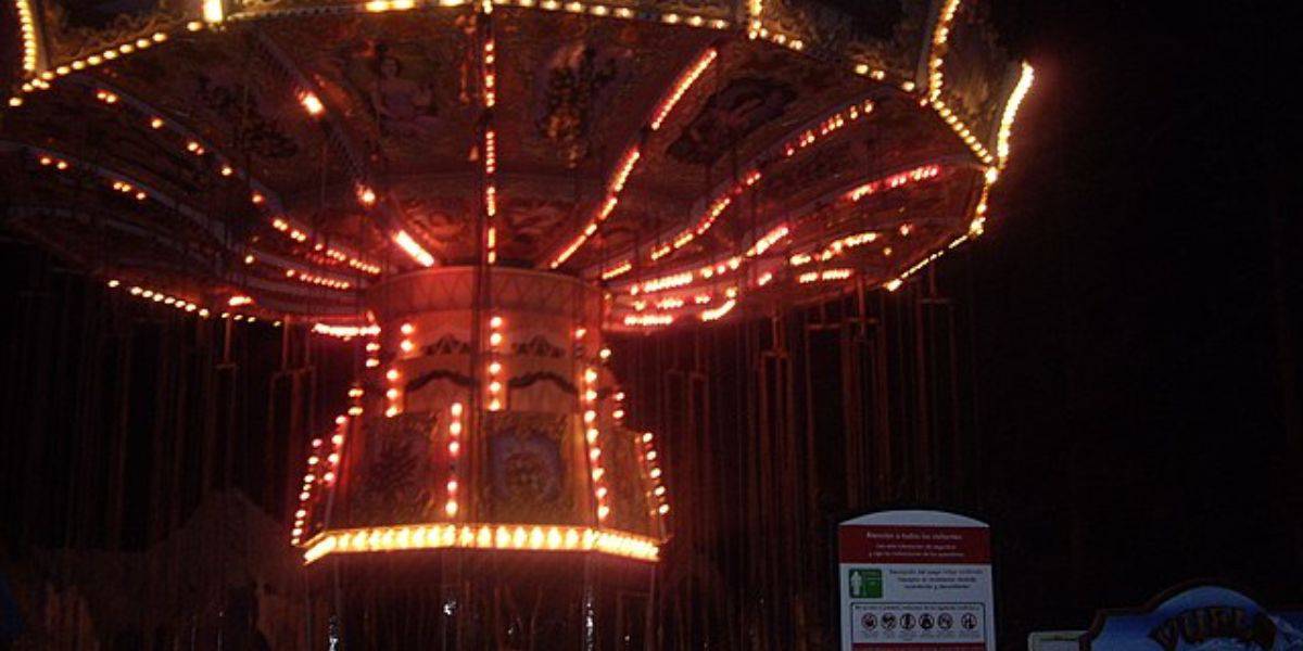 A brightly lit carousel swing ride at night.