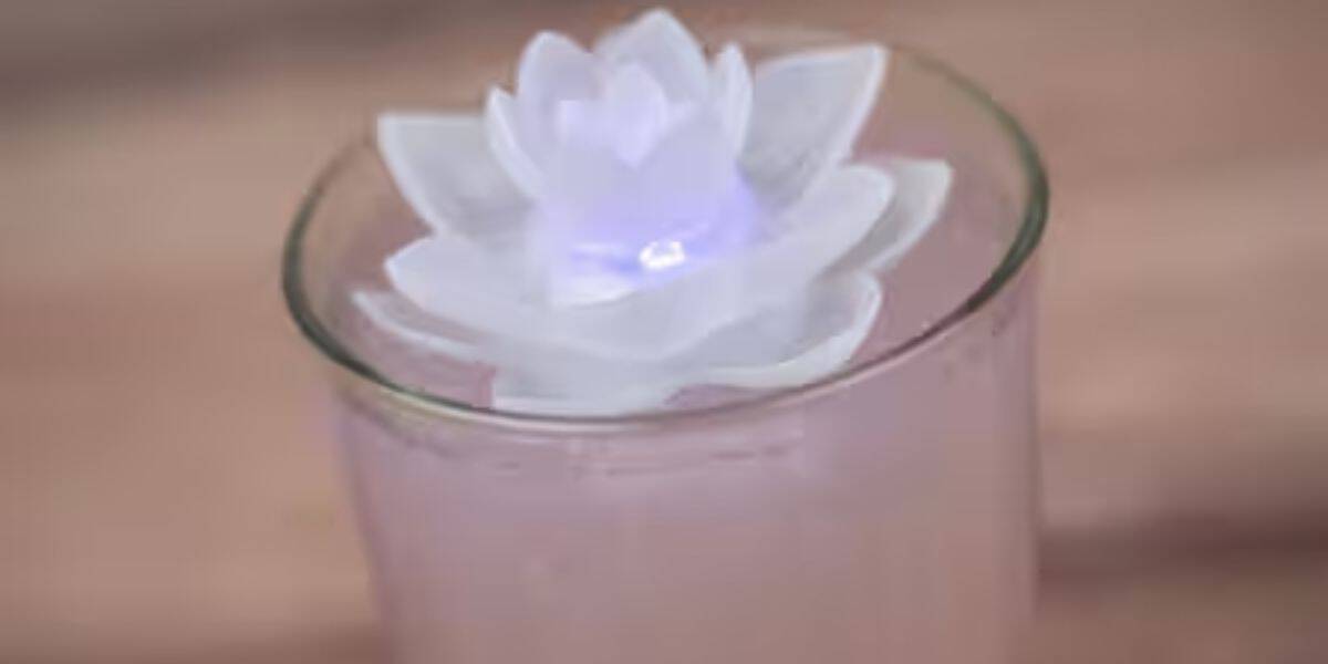 A glowing white lotus-shaped light floats on the Annual Passholder Frozen Lavender Lemonade available for a limited time at EPCOT.