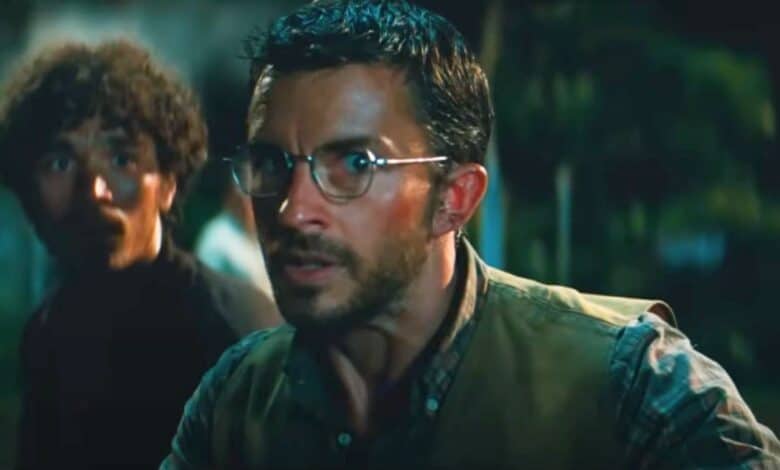 Jonathan Bailey looking at a raptor in 'Jurassic World Rebirth'