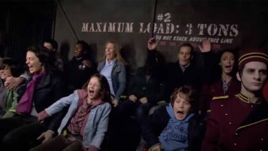 A group of people scream and laugh while riding an amusement park attraction. Behind them, a sign reads "Maximum Load: 3 Tons." A ride operator in a uniform sits calmly in the foreground.