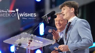 A young man in a light blue suit speaks at a podium with an NFL logo, while another man stands behind him smiling. The "Disney GMA Week of Wishes" and "Make-A-Wish" logos are displayed on the left.