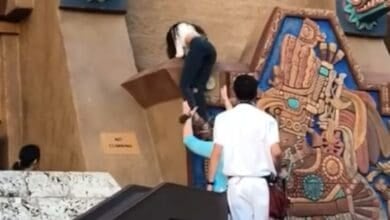 A person being helped climbing the EPCOT World Showcase Mexico Pavilion