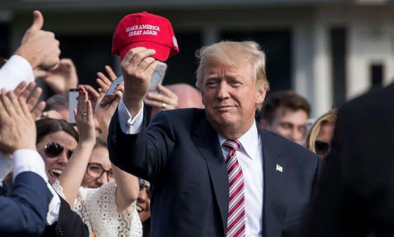 Donald Trump holds a MAGA hat